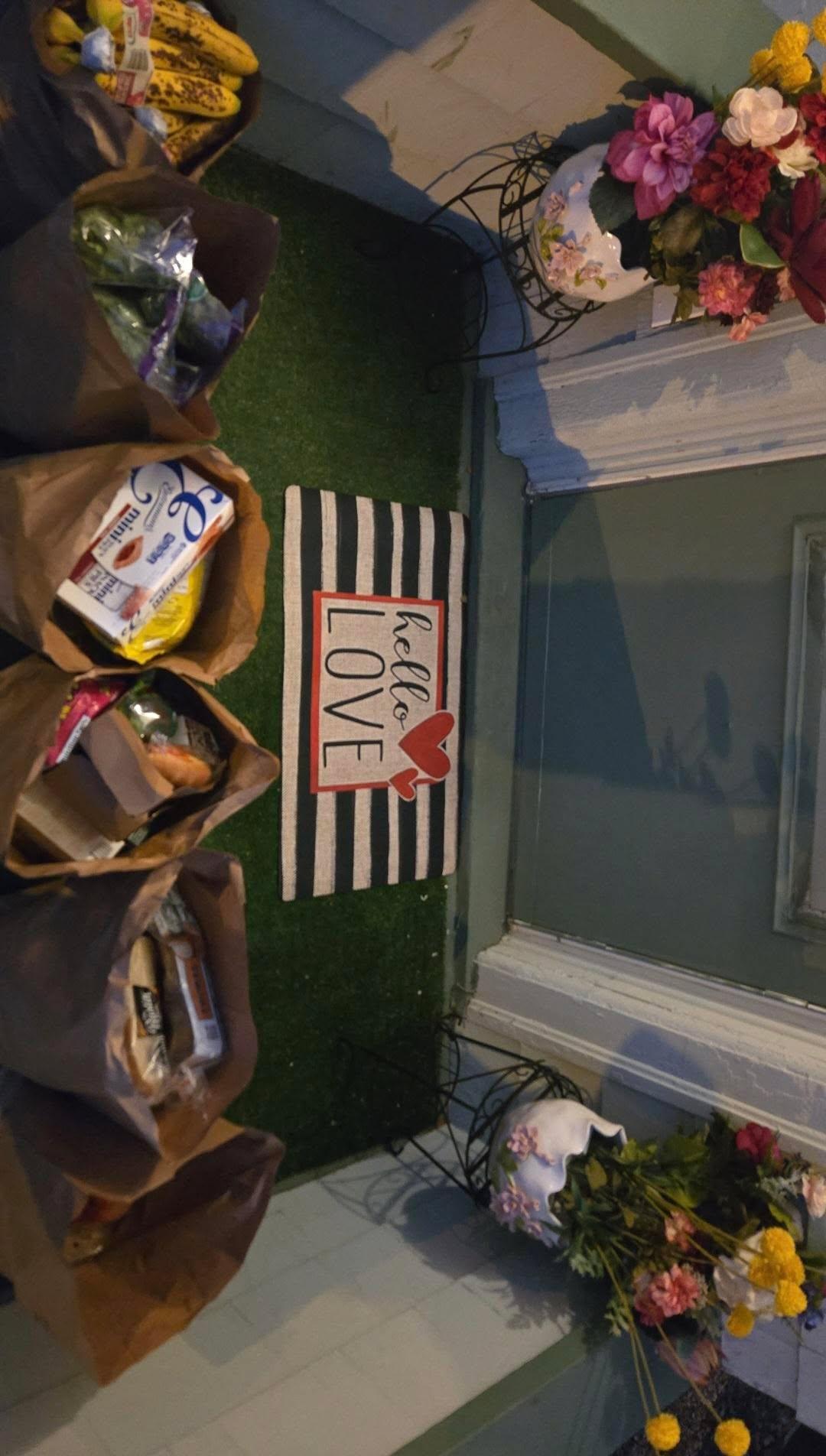 Grocery bags left on a doorstep beside a 'hello LOVE' mat